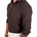 A man wearing a dark brown long-sleeve linen button-down shirt and off-white linen trousers, shown from a side profile against a white background.