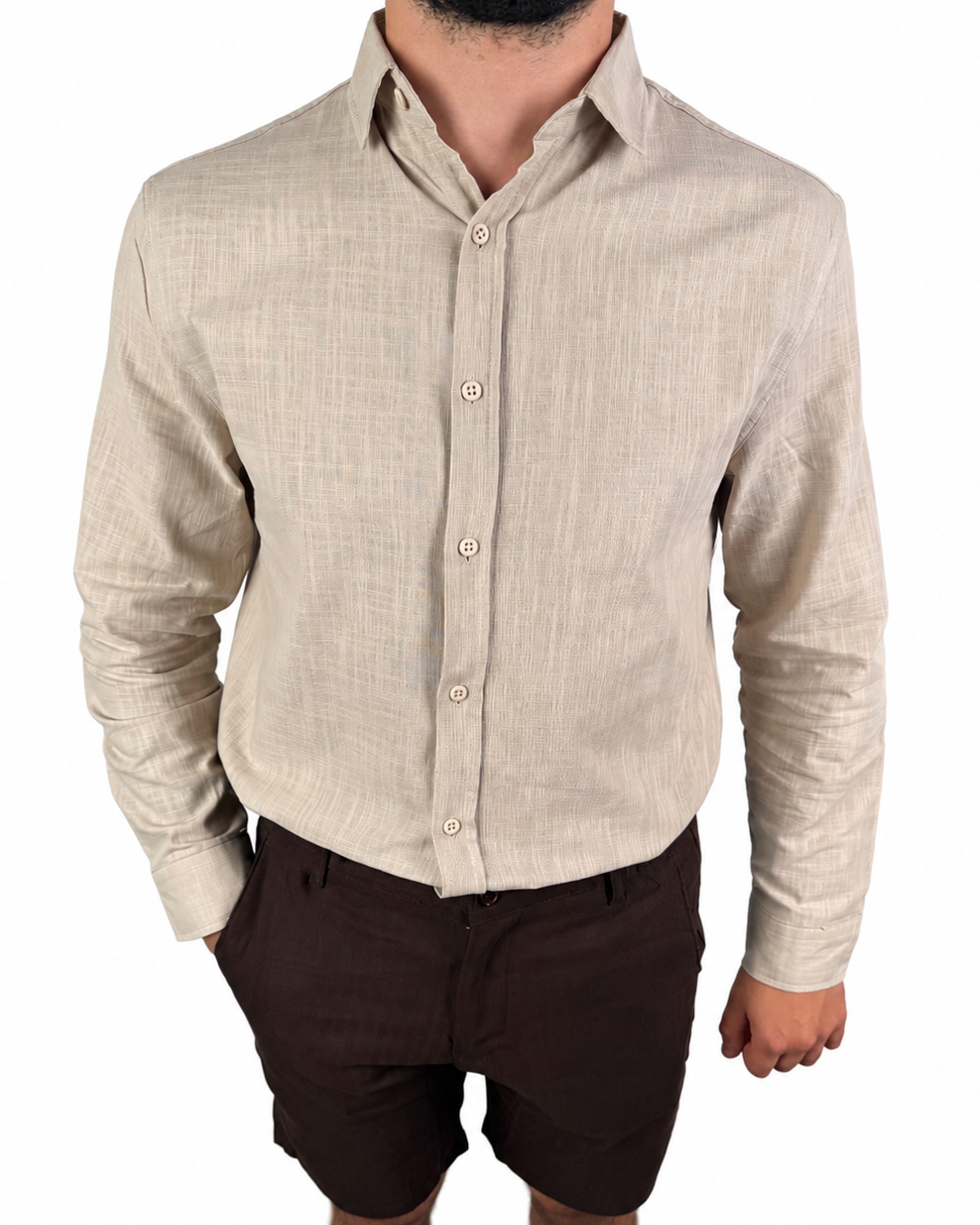 A man wearing a light beige linen long-sleeve button-down shirt and dark brown shorts, shown from the chin down against a plain white background.