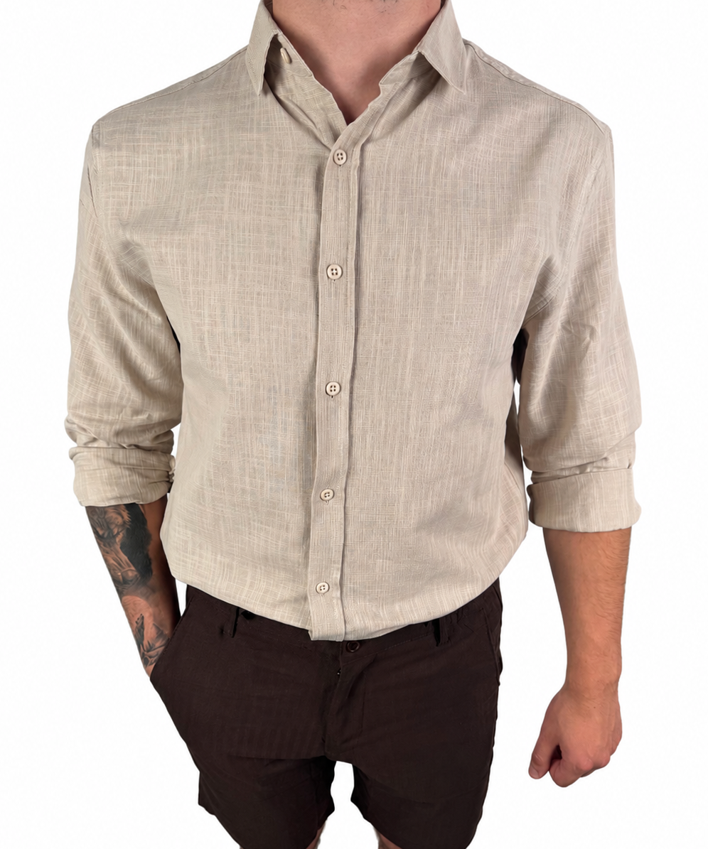 A man wearing a light beige linen long-sleeve button-down shirt and dark brown shorts, shown from the neck down against a plain white background.