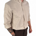 A man wearing a light beige linen button-down shirt with dark brown shorts, shown from the waist down against a plain white background.