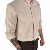 A man wearing a light beige linen button-down shirt with dark brown shorts, shown from the waist down against a plain white background.