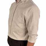 A man wearing a light beige linen long-sleeve button-down shirt and dark brown shorts, shown from a side profile against a white background.