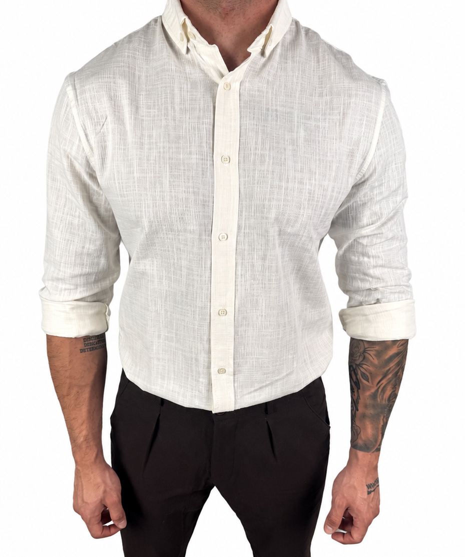 A man wearing a light beige linen long-sleeve button-down shirt with rolled-up sleeves and black trousers, shown from the neck down against a plain white background.