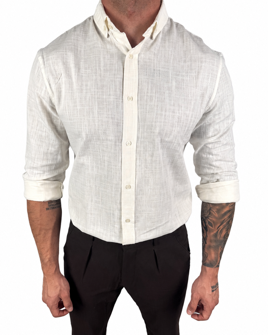 A man wearing a light beige linen long-sleeve button-down shirt with rolled-up sleeves and black trousers, shown from the neck down against a plain white background.