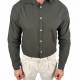 A man wearing a dark olive green long-sleeve button-down shirt and light beige trousers, shown from the neck down against a plain white background.