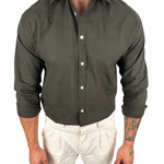A man wearing a dark olive green long-sleeve button-down shirt and off-white trousers, shown from the neck down against a plain white background.