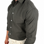 A man wearing a dark olive green long-sleeve button-down shirt and light beige trousers, shown from a side profile against a plain white background.
