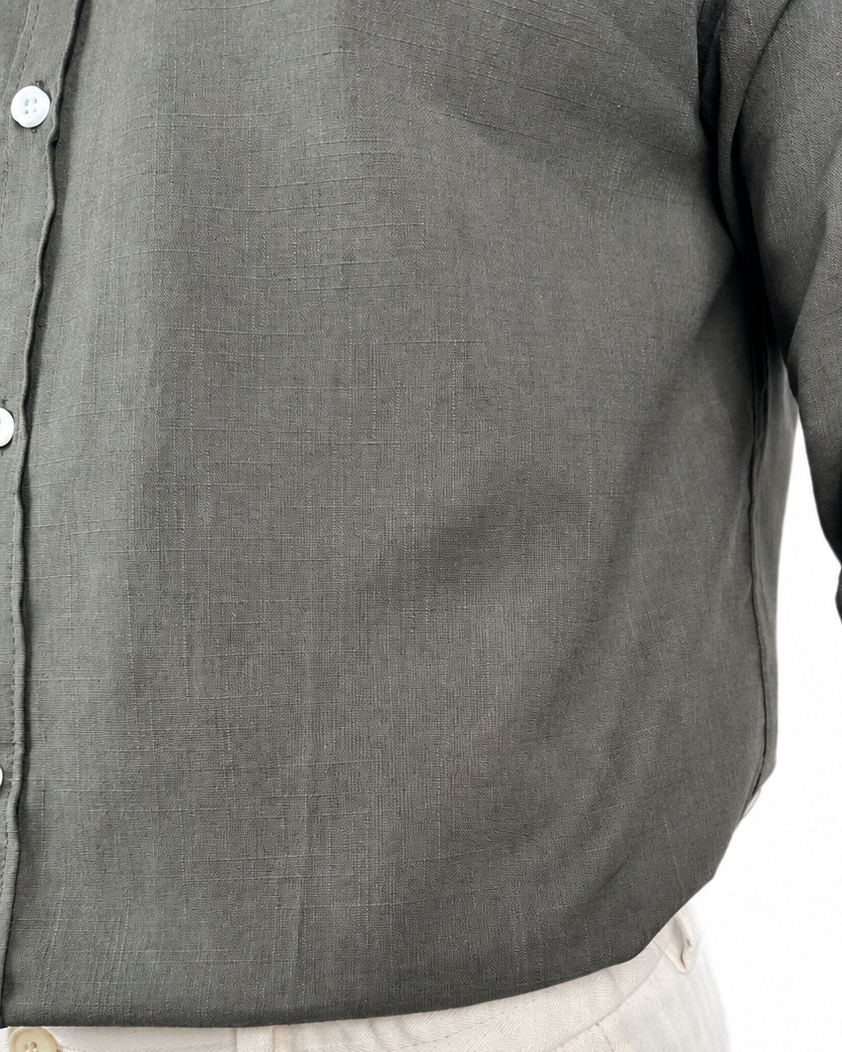 Close-up of a dark gray linen button-up shirt with a visible linen weave texture, worn by a model with light beige pants visible at the bottom.
