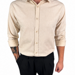 A man wearing a light beige linen button-down shirt with black trousers, shown from the neck down against a plain white background.