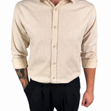A man wearing a light beige linen button-down shirt with black trousers, shown from the neck down against a plain white background.