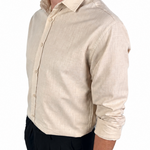 A man wearing a light beige linen button-down shirt with black trousers, shown from a side profile against a plain white background.