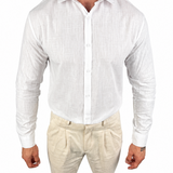 A man wearing a white long-sleeve linen button-up shirt and beige linen trousers, shown from the neck down against a plain white background.