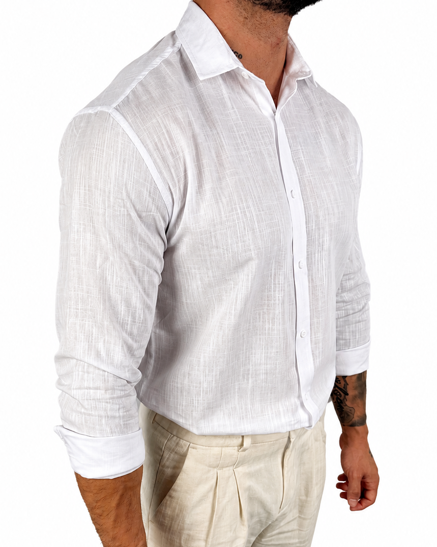 A man wearing a white long-sleeve linen button-down shirt and light beige trousers, shown from the waist up against a plain white background.