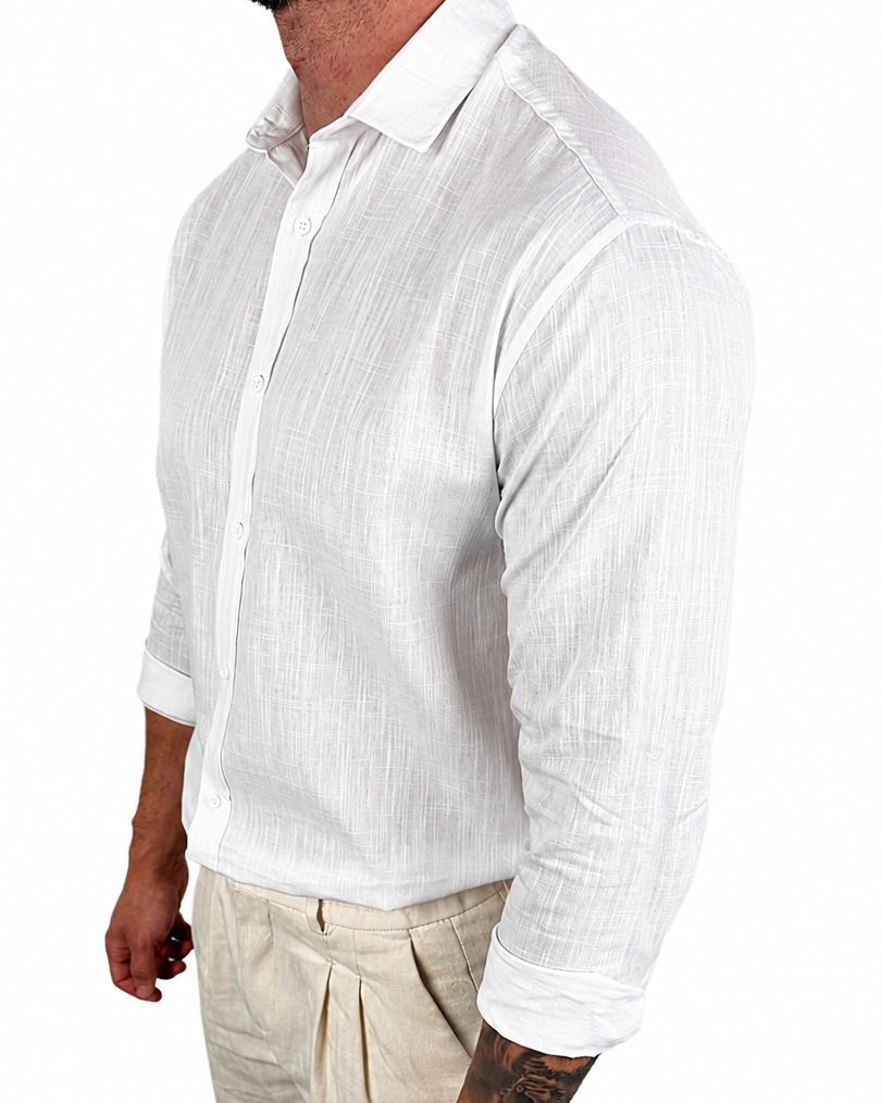 A man wearing a white long-sleeve linen button-down shirt and beige trousers, shown from the side against a plain white background.