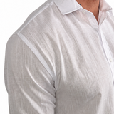 A close-up of a man wearing a white long-sleeve linen button-down shirt, showing the textured fabric and collar against a plain white background.
