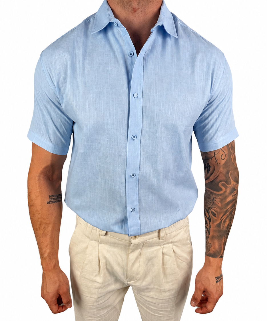 A man wearing a light blue short-sleeve button-up shirt and beige trousers, shown from the neck down against a plain white background.