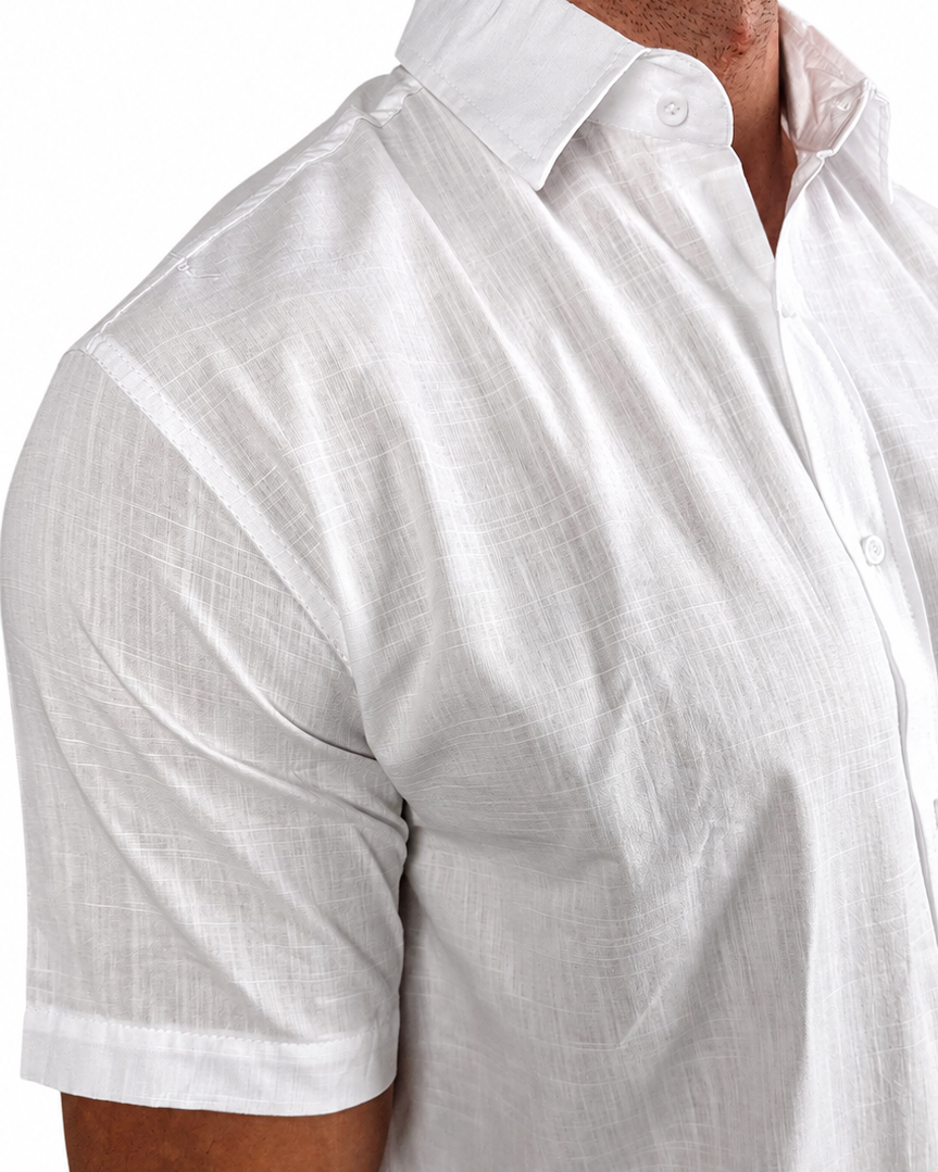 A close-up of a man wearing a white short-sleeve linen button-down shirt, showing the textured fabric and collar.