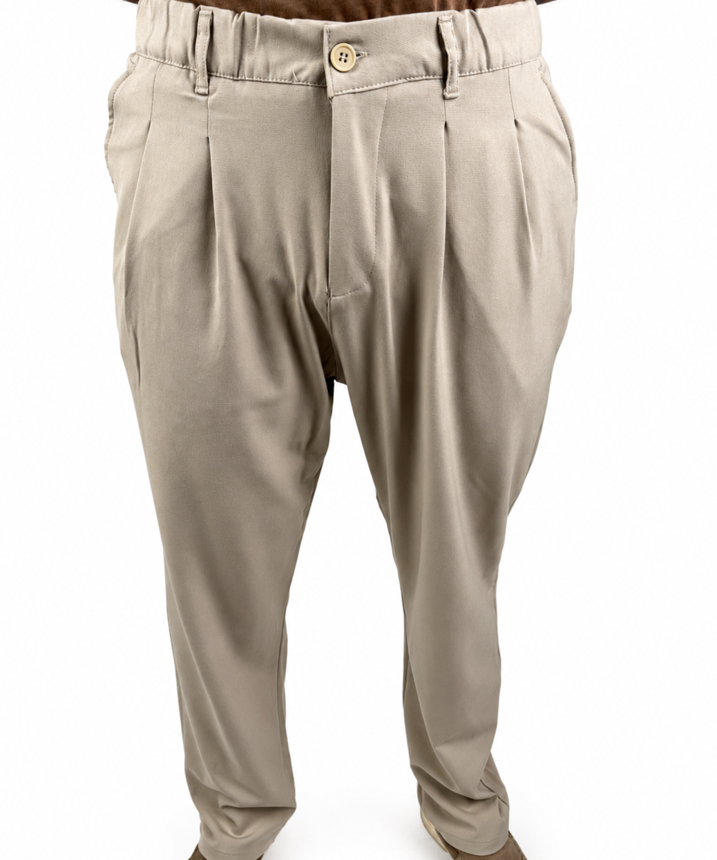 A pair of men's beige pleated trousers shown on a model from the waist down, paired with brown shoes and a brown shirt against a white background.