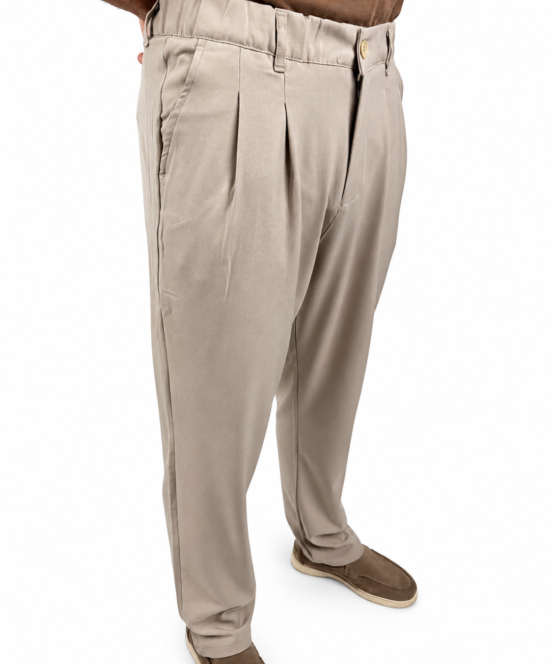 A person wearing light beige pleated trousers and brown slip-on shoes, shown from the waist down against a plain white background.