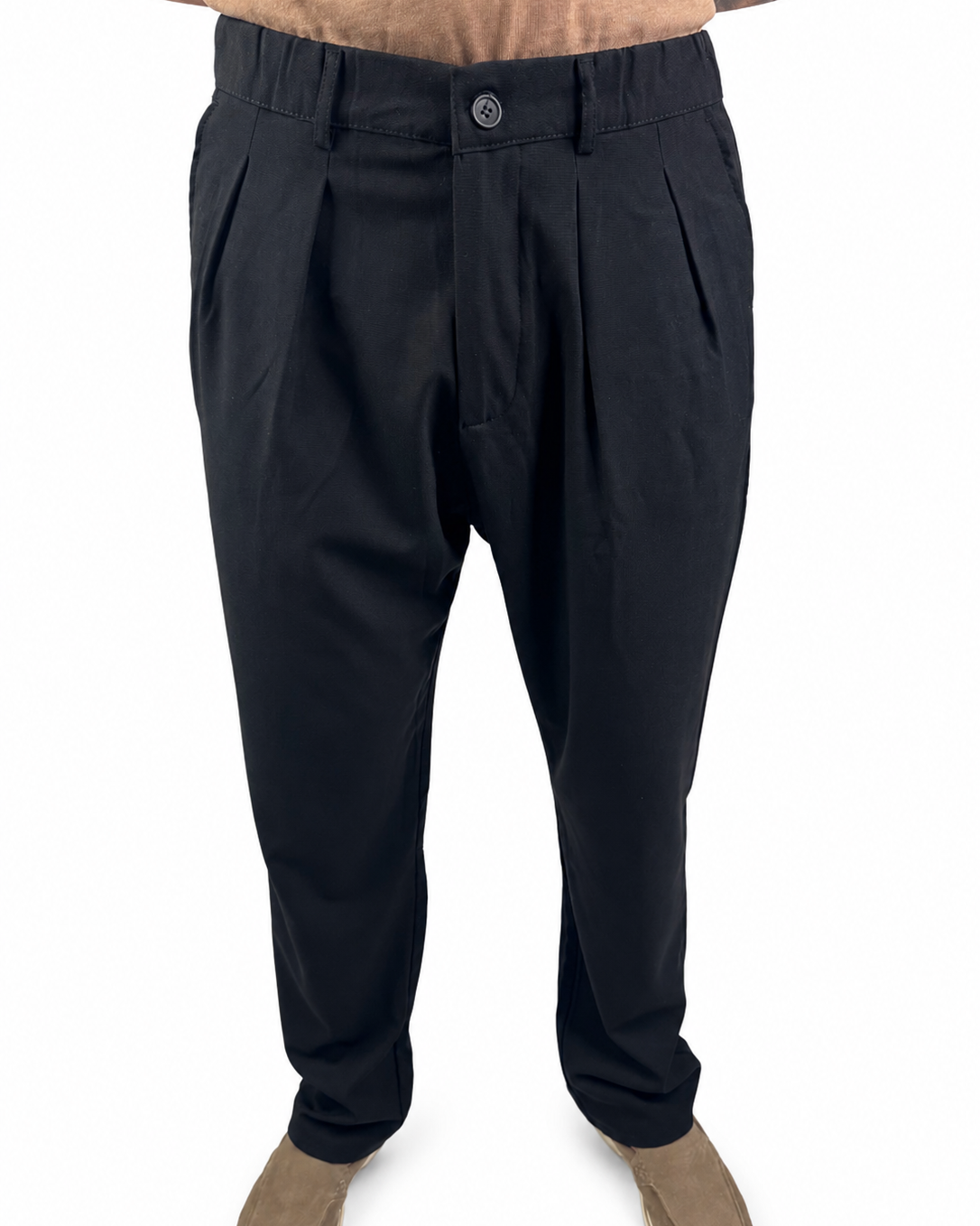Black pleated trousers shown on a model from the waist down, paired with tan suede shoes against a plain white background.