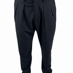 Black pleated trousers shown on a model from the waist down, paired with tan suede shoes against a plain white background.