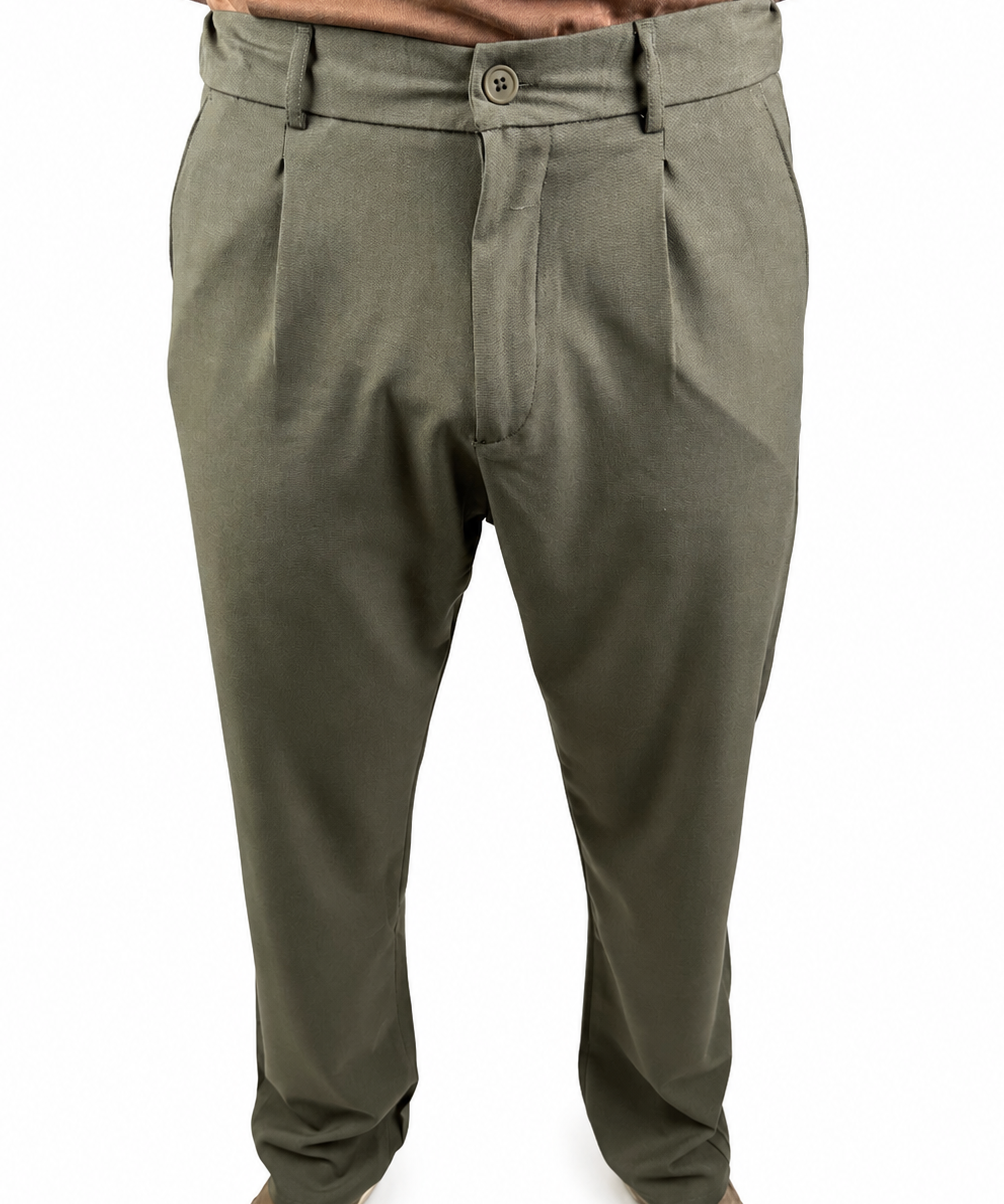A person wearing olive green dress pants with a button closure and belt loops, paired with a brown shirt and brown shoes, shown from the waist down on a white background.