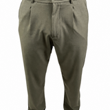 A person wearing olive green dress pants with a button closure and belt loops, paired with a brown shirt and brown shoes, shown from the waist down on a white background.