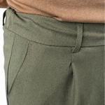 Close-up of a person wearing olive green trousers and a brown knit top against a white background.