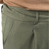 Close-up of a person wearing olive green trousers and a brown knit top against a white background.