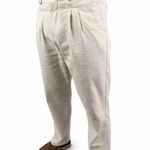A person wearing off-white pleated linen trousers and brown slip-on shoes, shown from the waist down against a plain white background.