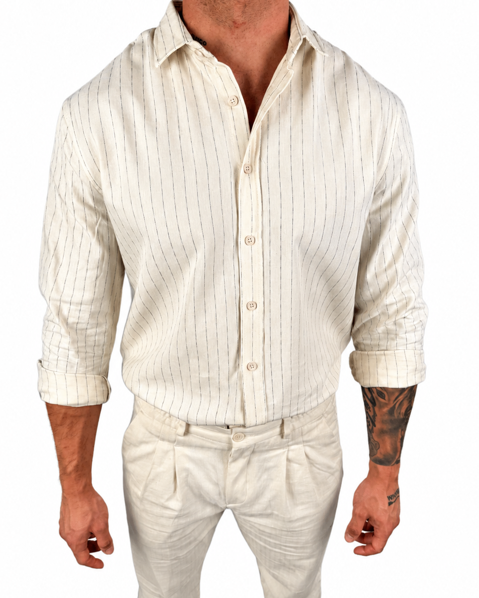 A man wearing a cream-colored linen shirt and matching trousers with thin vertical stripes, shown from the neck down against a plain white background.