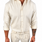 A man wearing a cream-colored linen shirt and matching trousers with thin vertical stripes, shown from the neck down against a plain white background.