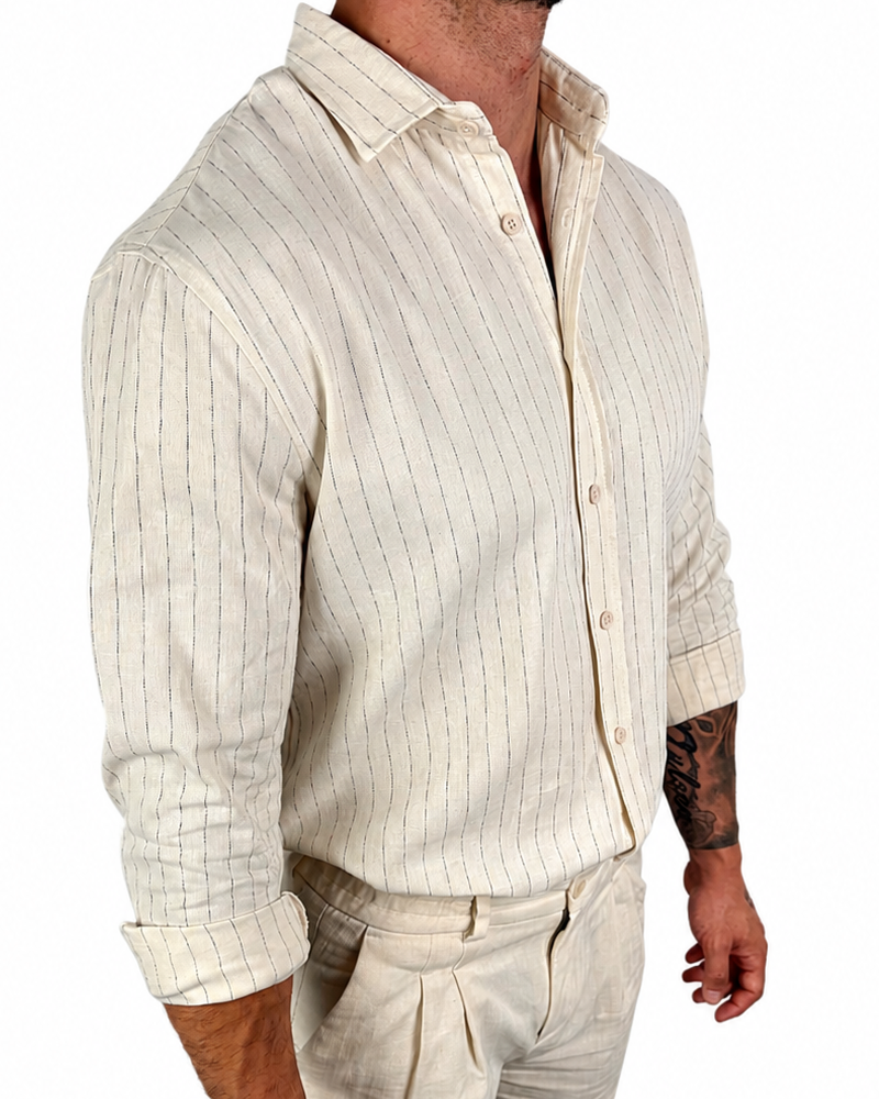 A man wearing a cream-colored linen shirt and matching linen trousers, shown from the neck down against a plain white background.