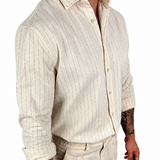 A man wearing a cream-colored linen shirt and matching linen trousers, shown from the neck down against a plain white background.