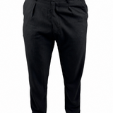 Black slim-fit trousers shown on a model from the waist down, paired with a tan shirt and beige slip-on shoes against a plain white background.