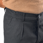Close-up of a person wearing dark charcoal gray trousers and a tan knit top against a plain white background.