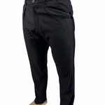 A person wearing black slim-fit trousers, shown from the waist down against a plain white background. The model is also wearing a tan shirt and tan slip-on shoes.
