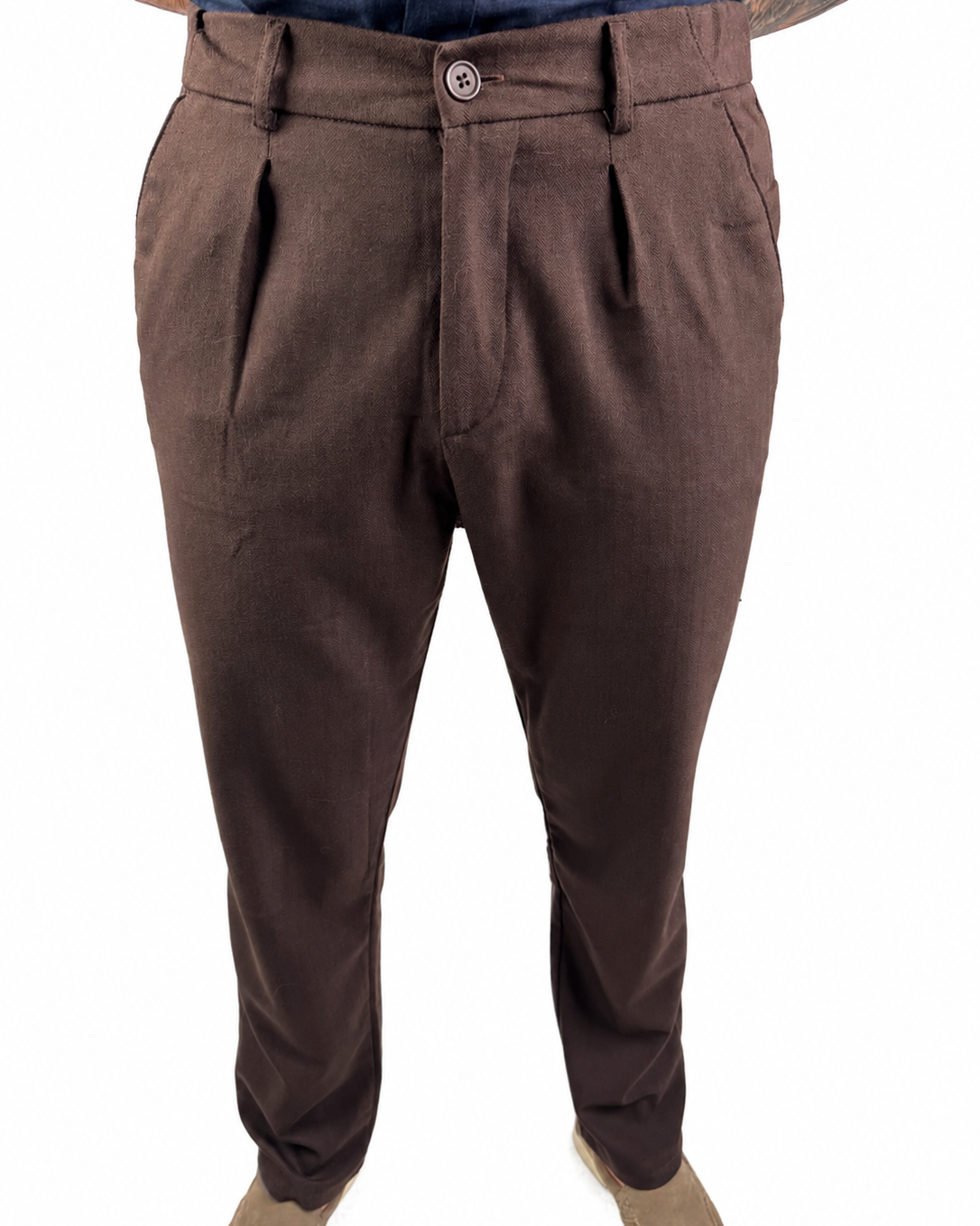 A pair of men's brown pleated trousers shown on a model from the waist down, paired with beige shoes against a plain white background.