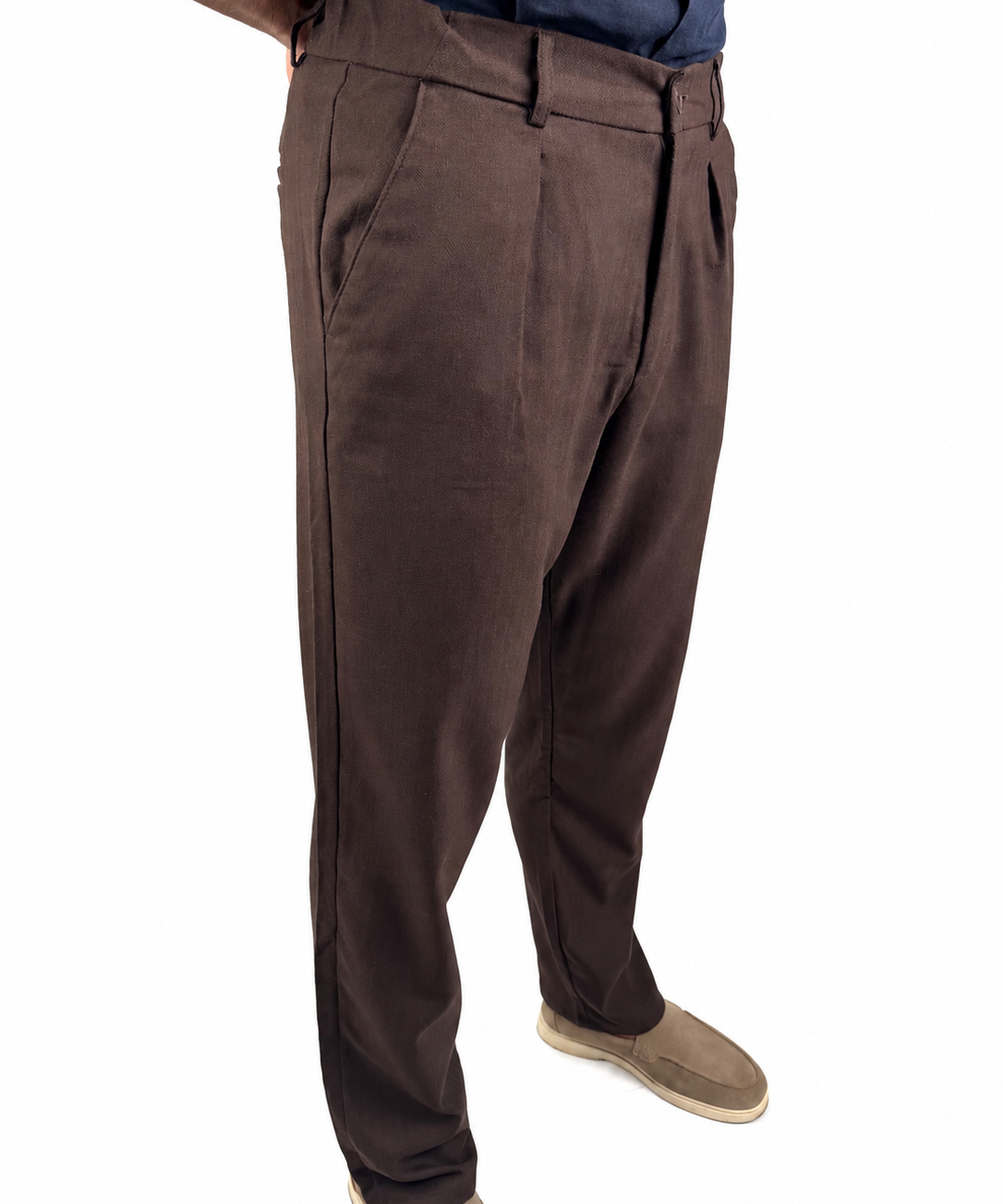 A person wearing dark brown dress pants with a blue shirt and tan shoes, shown from the waist down on a white background.