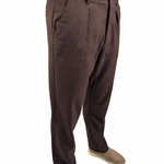 A person wearing dark brown dress pants with a blue shirt and tan shoes, shown from the waist down on a white background.