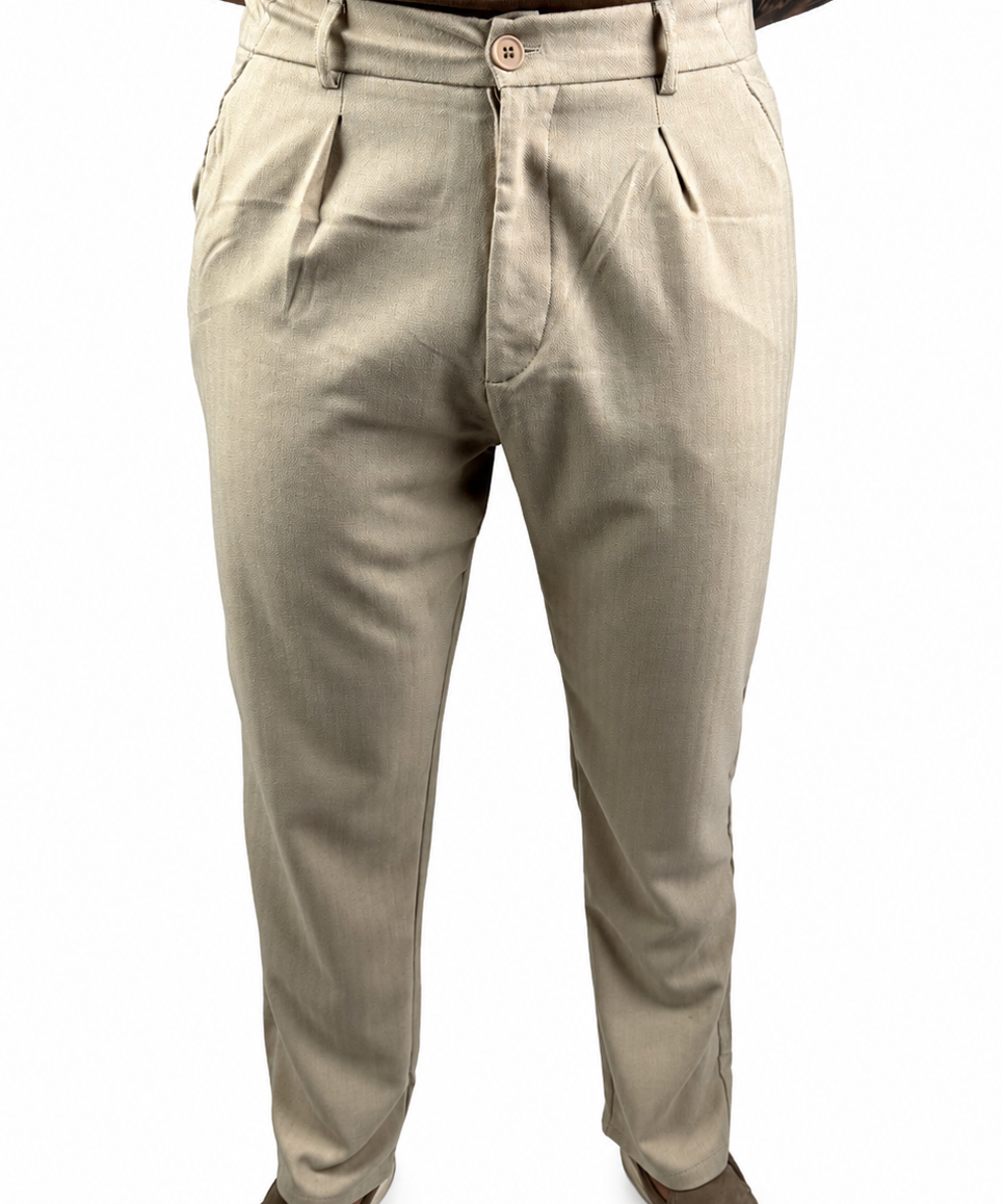 A person wearing light beige chinos or casual trousers, paired with a brown t-shirt and brown shoes, shown from the waist down against a white background.