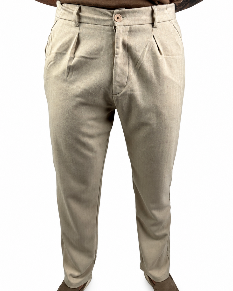 A person wearing light beige chinos or casual trousers, paired with a brown t-shirt and brown shoes, shown from the waist down against a white background.