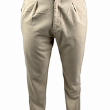 A person wearing light beige chinos or casual trousers, paired with a brown t-shirt and brown shoes, shown from the waist down against a white background.