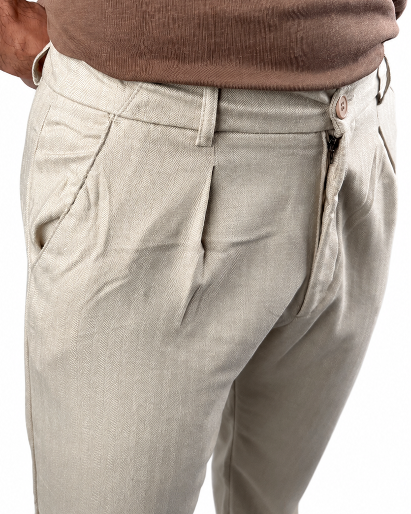 Close-up of a person wearing light beige chinos with a brown t-shirt, showing the side pocket and waist area against a white background.