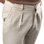 Close-up of a person wearing light beige chinos with a brown t-shirt, showing the side pocket and waist area against a white background.