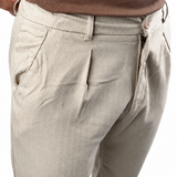 Close-up of a person wearing light beige chinos with a brown t-shirt, showing the side pocket and waist area against a white background.