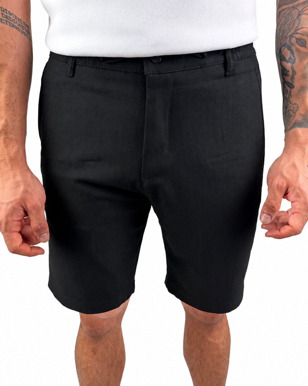 A man wearing black tailored shorts and a white t-shirt, cropped from the chest down, standing against a plain white background.