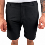 A man wearing black tailored shorts and a white t-shirt, cropped from the chest down, standing against a plain white background.