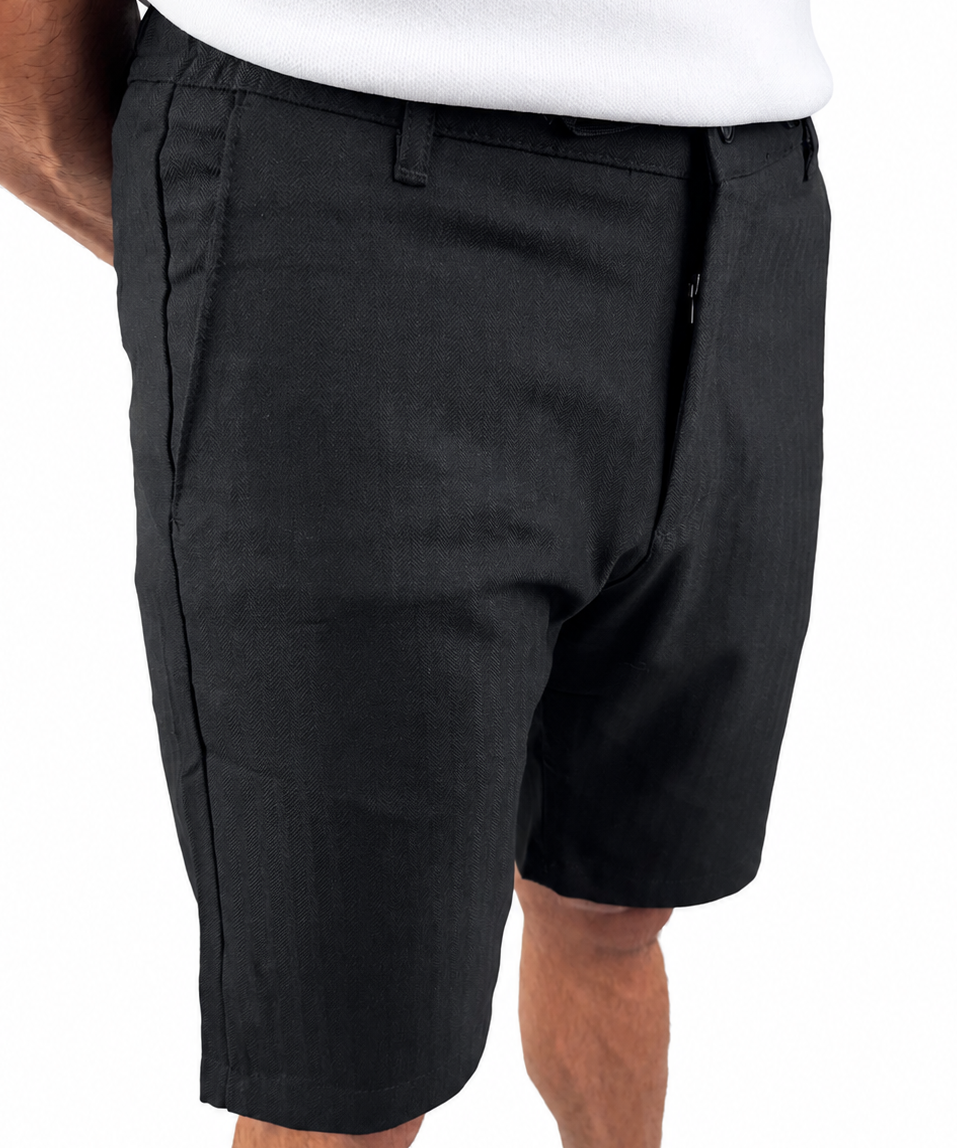 A person wearing black knee-length shorts with a white top and tan shoes, shown from the waist down against a plain white background.