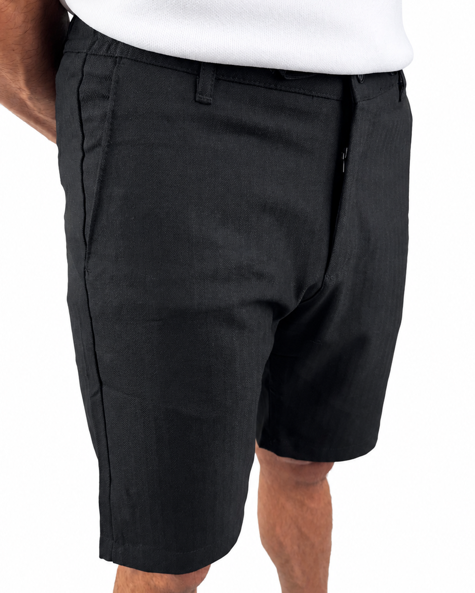 A person wearing black knee-length shorts with a white top and tan shoes, shown from the waist down against a plain white background.